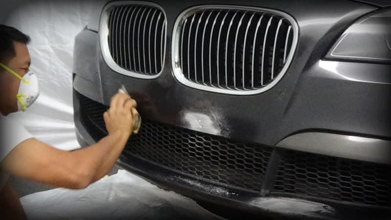 A scuffed bumper being repaired and refinished