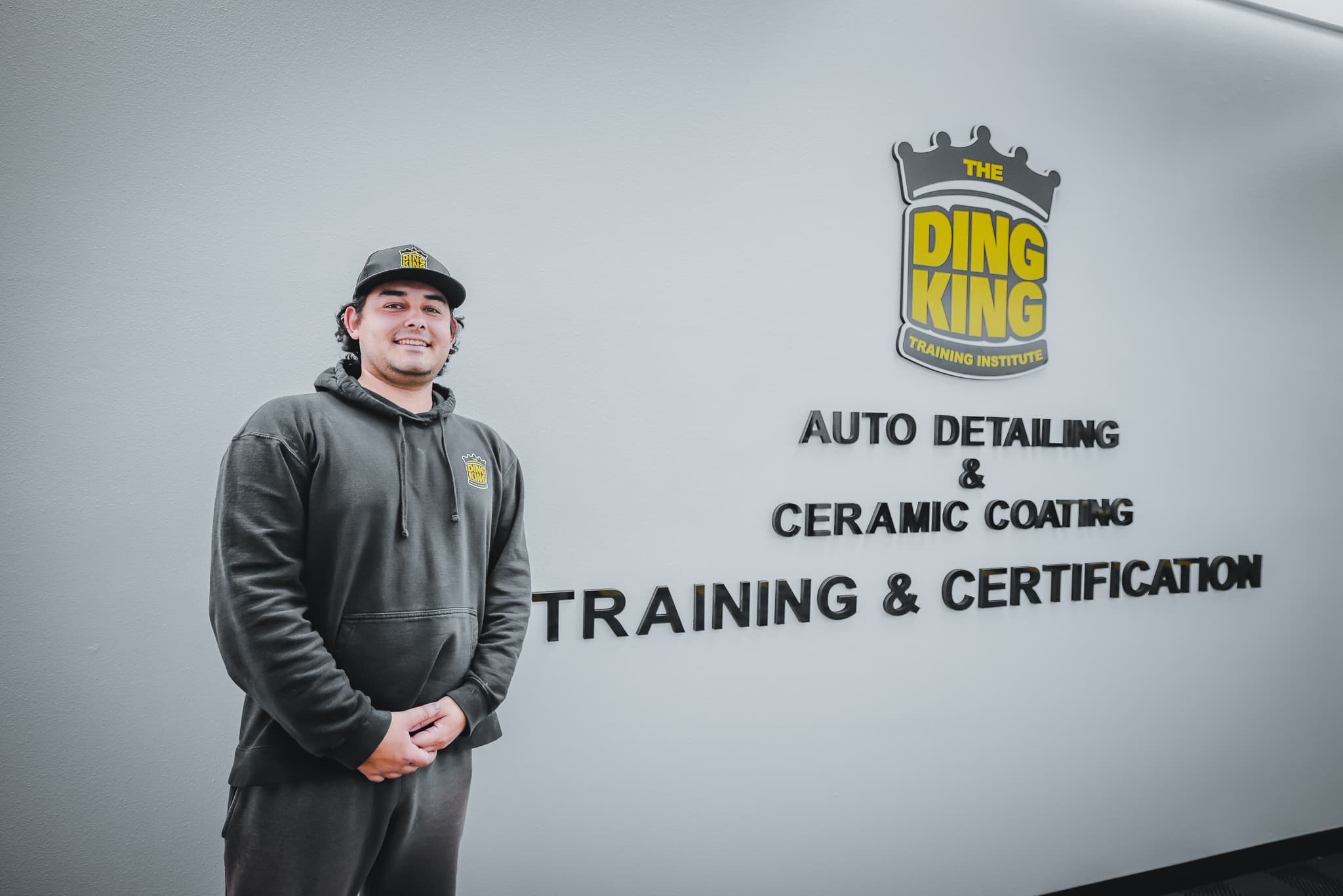 A Graduates to Greatness student outside a Ding King Training Institute center, where hands-on automotive training and certification take place