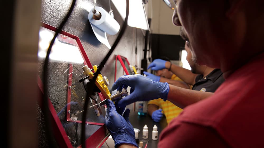 A technician repairing a chip in an automotive windshield